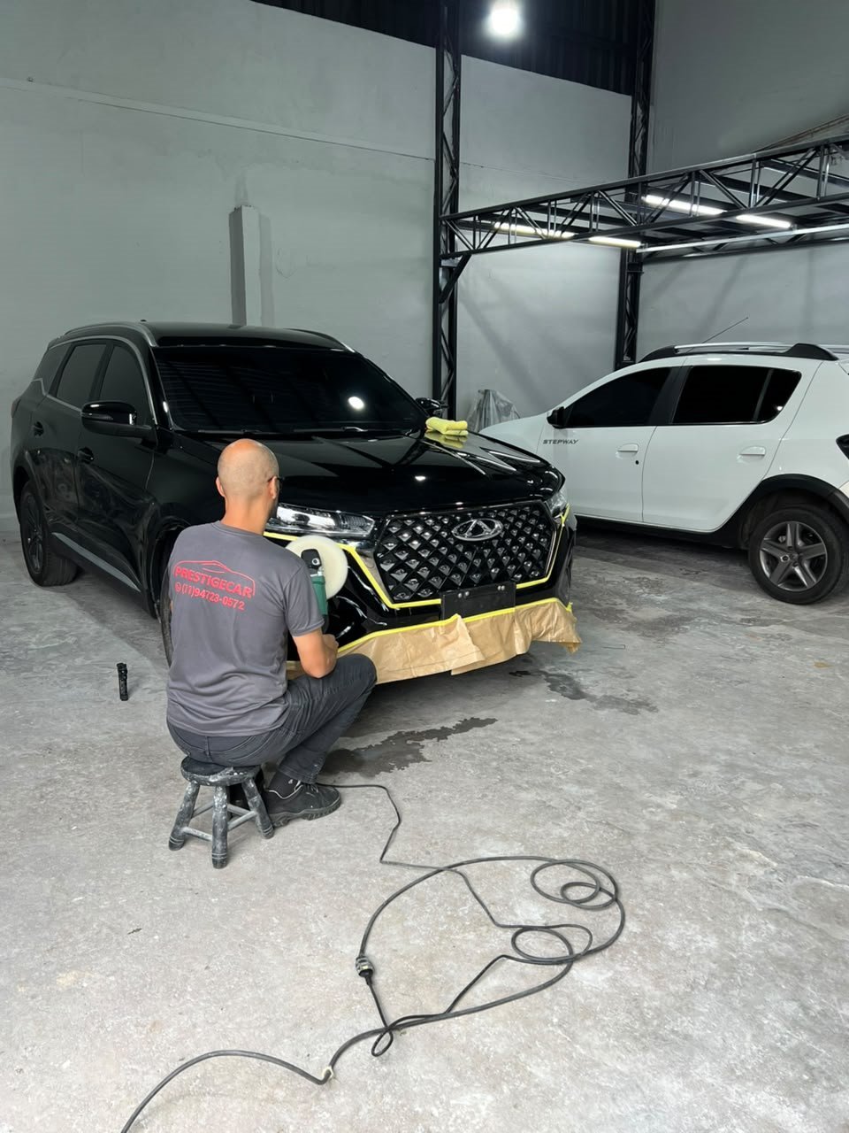 Profissional polindo um SUV preto no interior da oficina